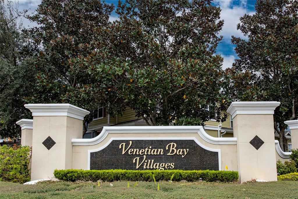 A stone monument sign for Venetian Bay Villages stands in front of large trees — 2270 SAN VITAL DRIVE UNIT 107, KISSIMMEE, FL