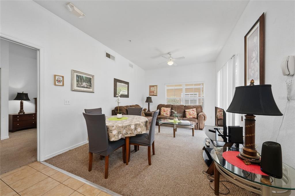 A living and dining area with carpeted floors, a round table, and brown sofas — 2270 SAN VITAL DRIVE UNIT 107, KISSIMMEE, FL