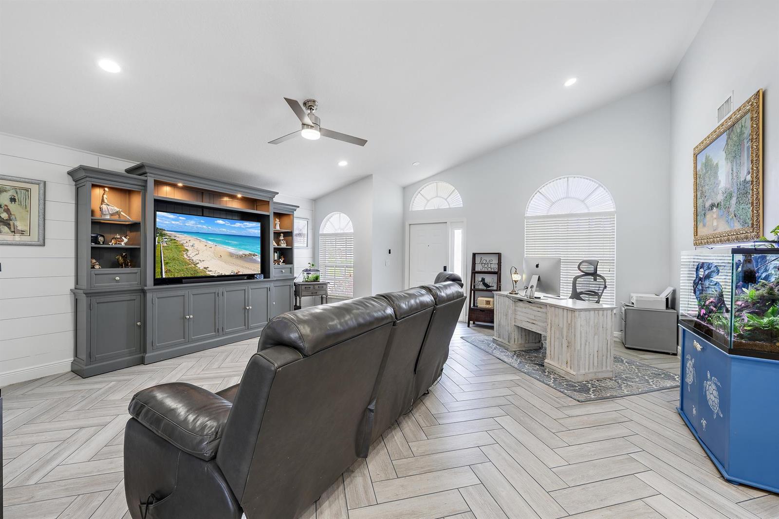 A living room features a large gray entertainment center, a leather sofa, and a desk — 1875 Oak Berry Circle, Wellington FL 33414, WELLINGTON, FL