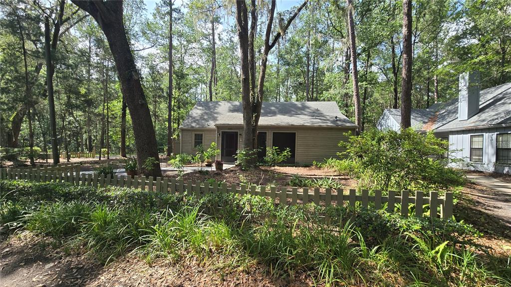 A tan house with a screened porch and a concrete walkway surrounded by wooded landscaping — 5201 SW 86 TERRACE, GAINESVILLE, FL