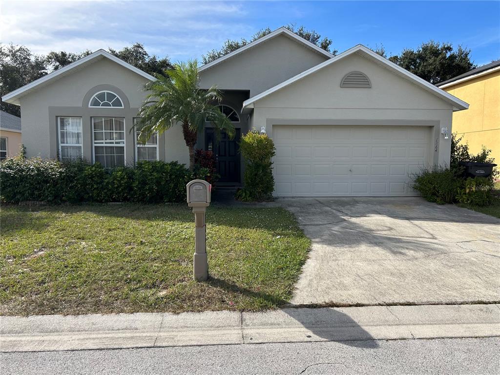 A single-story house with a beige exterior, a two-car garage, and a front lawn — 1864 EMILY DRIVE, WINTER HAVEN, FL