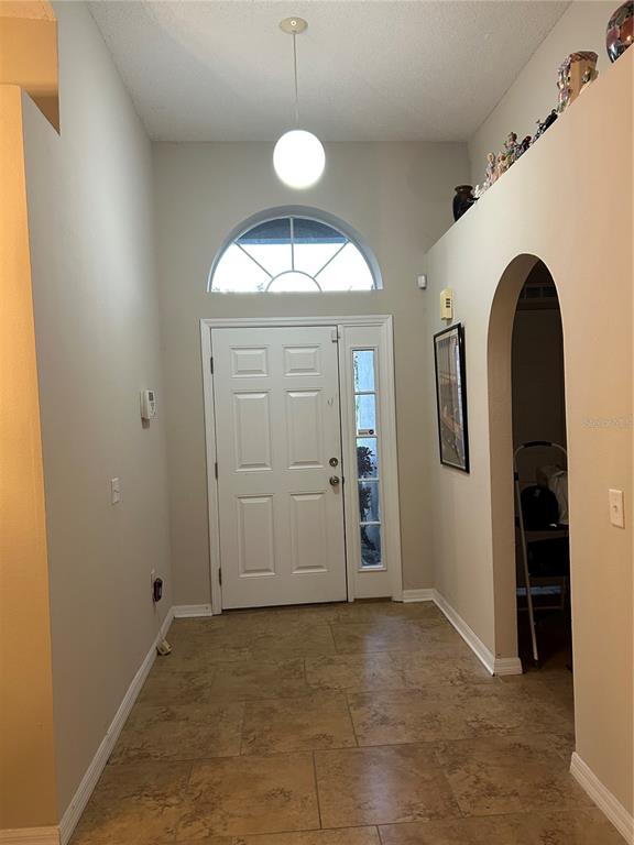 A dining area features a round table, chairs, and a chandelier under a vaulted ceiling — 1864 EMILY DRIVE, WINTER HAVEN, FL