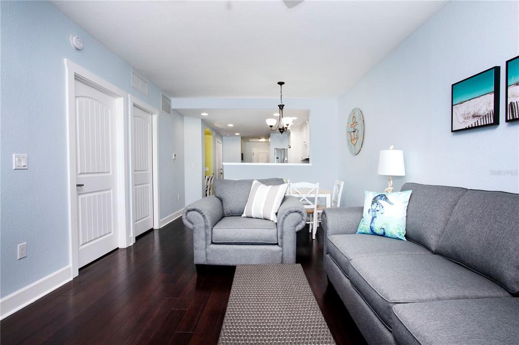 A living room features dark wood floors, gray furniture, and a view into the kitchen — 399 2ND STREET UNIT 417, INDIAN ROCKS BEACH, FL