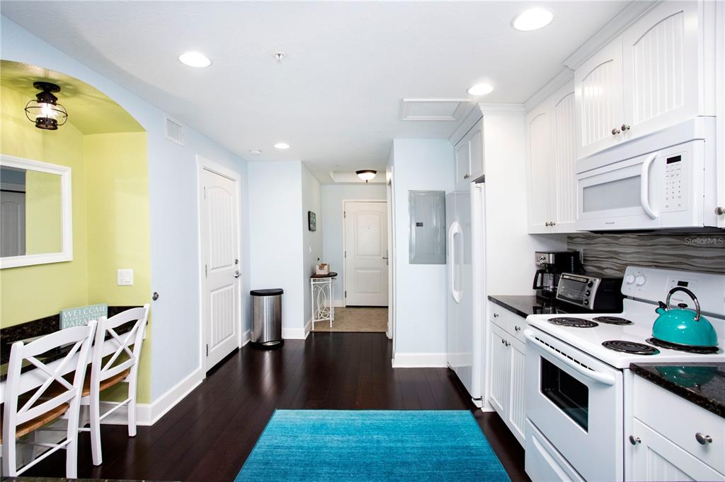 A kitchen with white cabinets, dark wood floors, and a bright blue area rug — 399 2ND STREET UNIT 417, INDIAN ROCKS BEACH, FL
