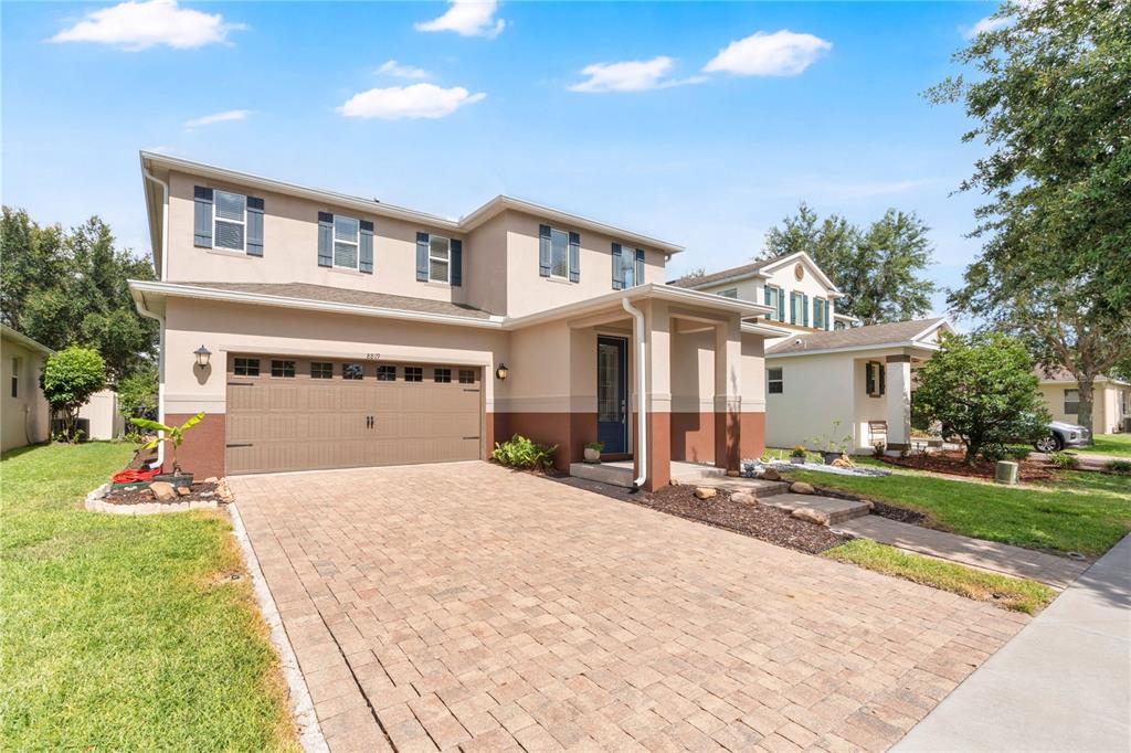 A two-story house with a tan stucco exterior, brown trim, and a paved driveway — 8819 TATARA STREET, ORLANDO, FL
