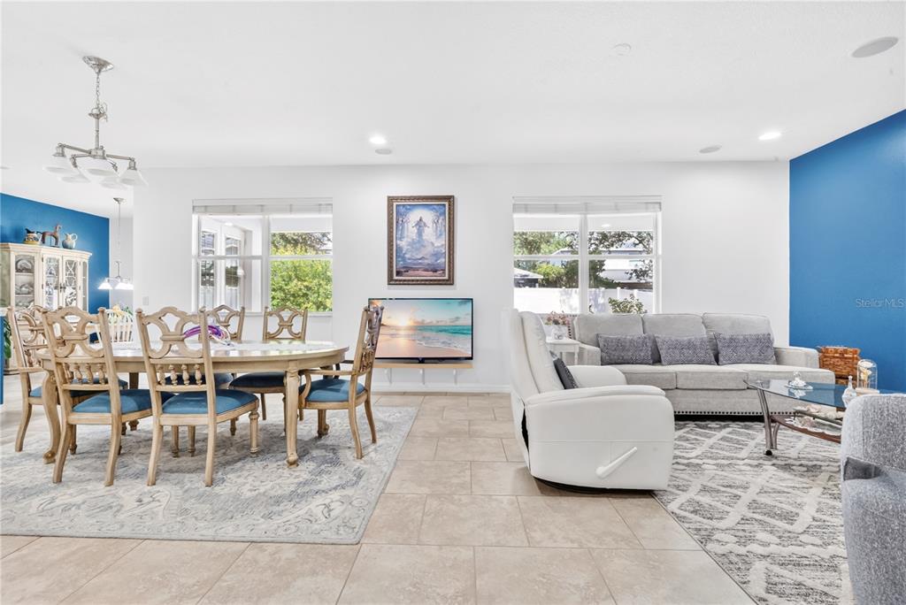 An open-concept living and dining area features tile flooring, blue accent walls, and large windows — 8819 TATARA STREET, ORLANDO, FL