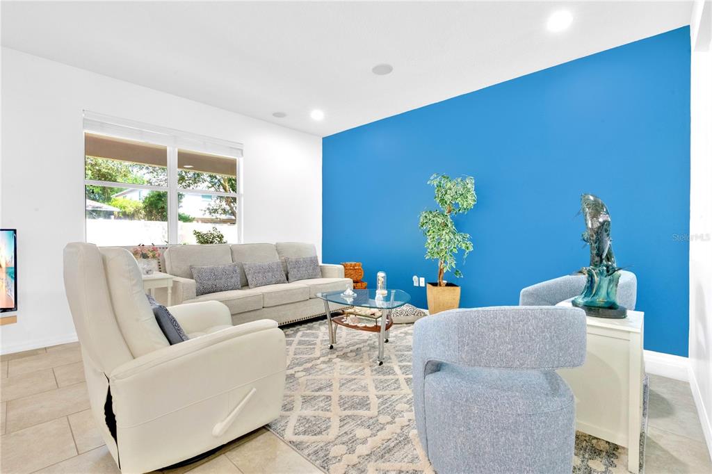 A living room features a bright blue accent wall, light tile flooring, and neutral furniture — 8819 TATARA STREET, ORLANDO, FL