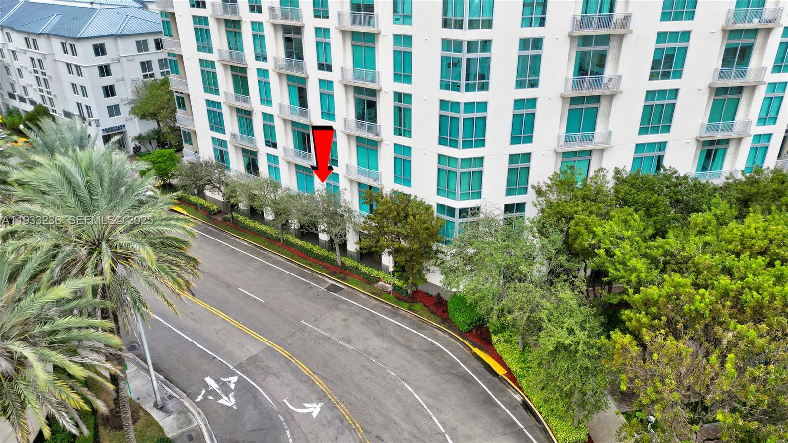 An aerial view shows the exterior of a multi-story residential building with a red arrow — 9025 S DADELAND BLVD, Miami FL 33156, MIAMI, FL
