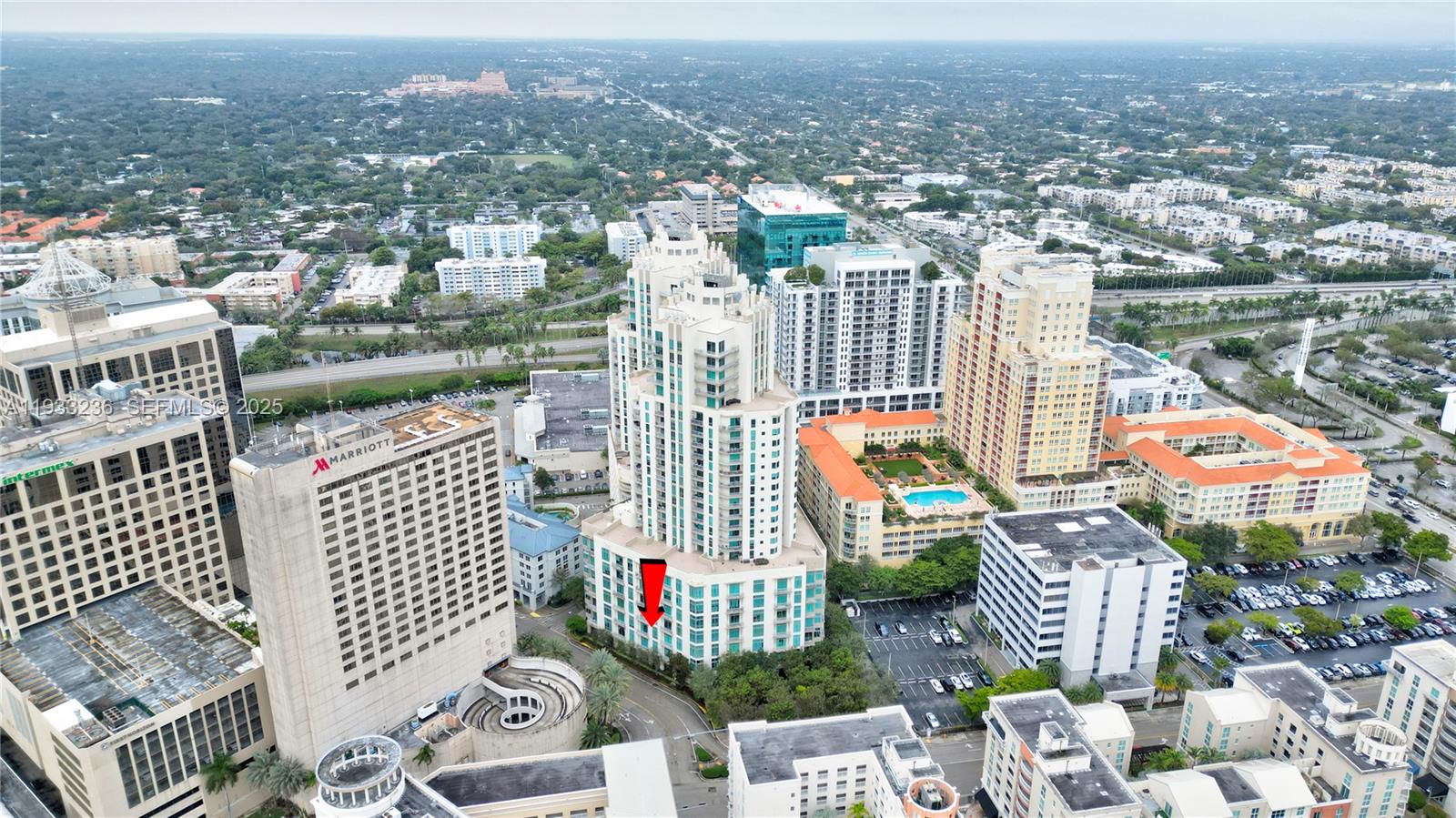 An aerial view shows a tall residential tower with a red arrow pointing toward its base — 9025 S DADELAND BLVD, Miami FL 33156, MIAMI, FL