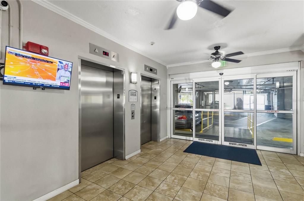 An elevator lobby with tiled floors, two stainless steel elevators, and glass doors to parking — 13427 BLUE HERON BEACH DRIVE UNIT 104, ORLANDO, FL