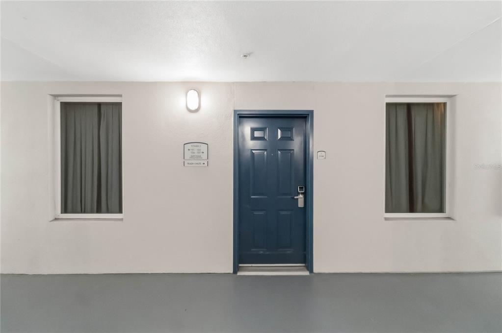 A blue door is centered between two windows on a plain, light-colored exterior wall — 13427 BLUE HERON BEACH DRIVE UNIT 104, ORLANDO, FL