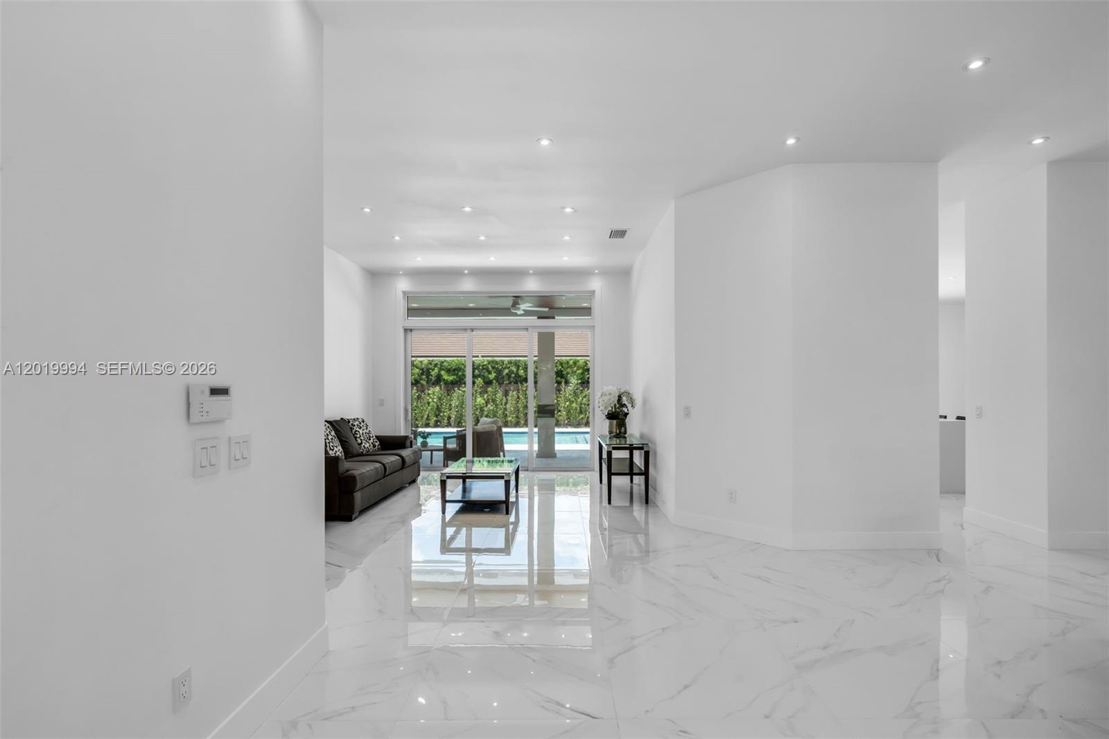A bright living room features white marble floors, recessed lighting, and sliding glass doors — 7262 SW 120th Ave, Miami FL 33183, MIAMI, FL