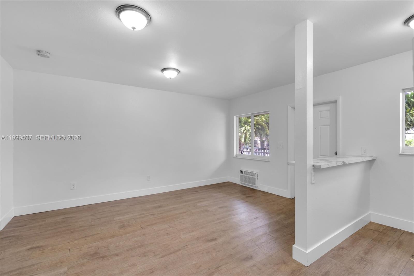 An empty room features white walls, wood-look flooring, two ceiling lights, and a breakfast bar — 5549 NE Miami Ct # 1, Miami FL 33137, MIAMI, FL