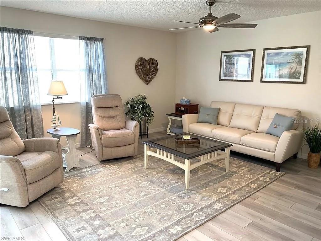 A living room features a beige sofa, two recliners, a coffee table, and light flooring — 1712 MORELOS ROAD, THE VILLAGES, FL
