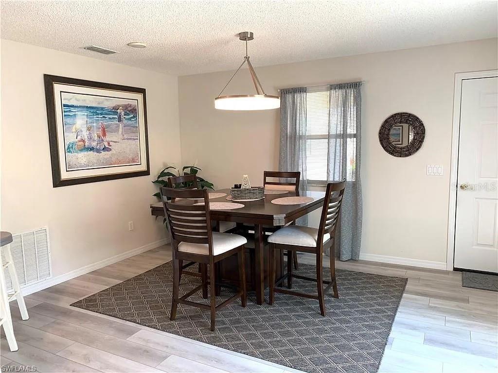 A kitchen with white cabinets, stainless steel appliances, and a dining area in the background — 1712 MORELOS ROAD, THE VILLAGES, FL
