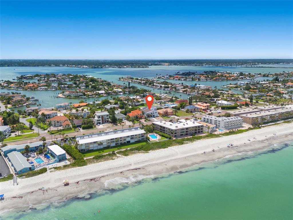 An aerial view shows a coastal neighborhood with beachfront condominiums, houses, and a red location pin — 3221 GULF BOULEVARD, BELLEAIR BEACH, FL