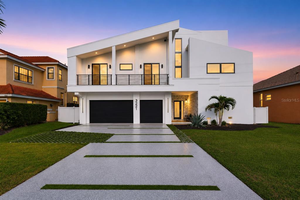 A modern two-story white house features a two-car garage and a paved driveway with grass — 3221 GULF BOULEVARD, BELLEAIR BEACH, FL