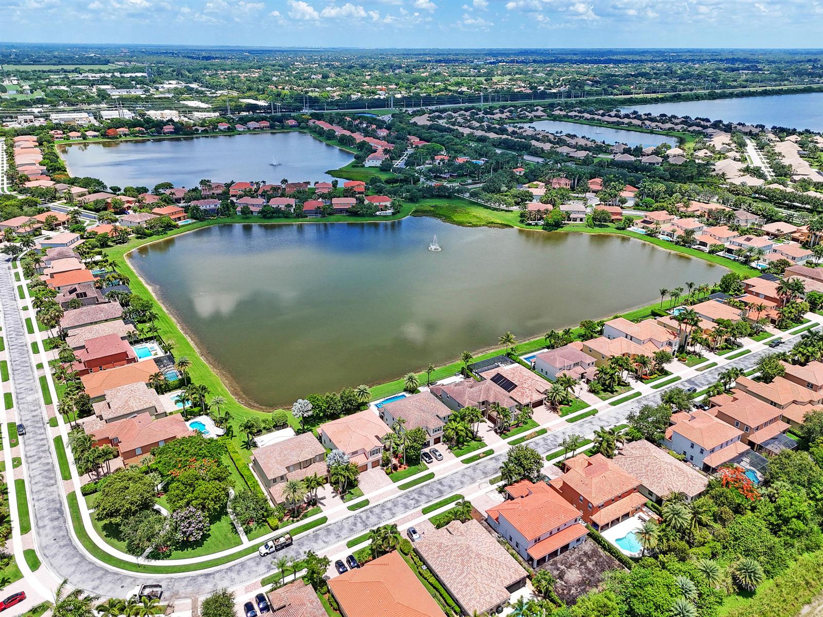 An aerial view of a suburban neighborhood featuring houses surrounding a large central lake — 10519 Longleaf Lane, Wellington FL 33414, WELLINGTON, FL