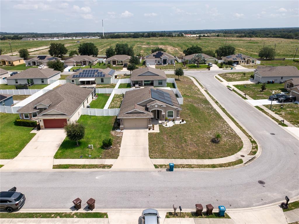 An aerial view shows suburban houses with solar panels and driveways in a residential neighborhood — 2628 SUNSET CIRCLE, LAKE WALES, FL