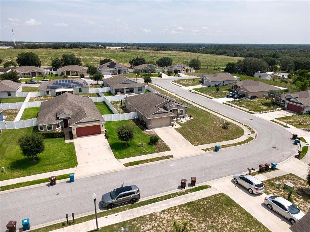 An aerial view shows a suburban neighborhood with single-family homes, paved streets, and parked cars — 2628 SUNSET CIRCLE, LAKE WALES, FL