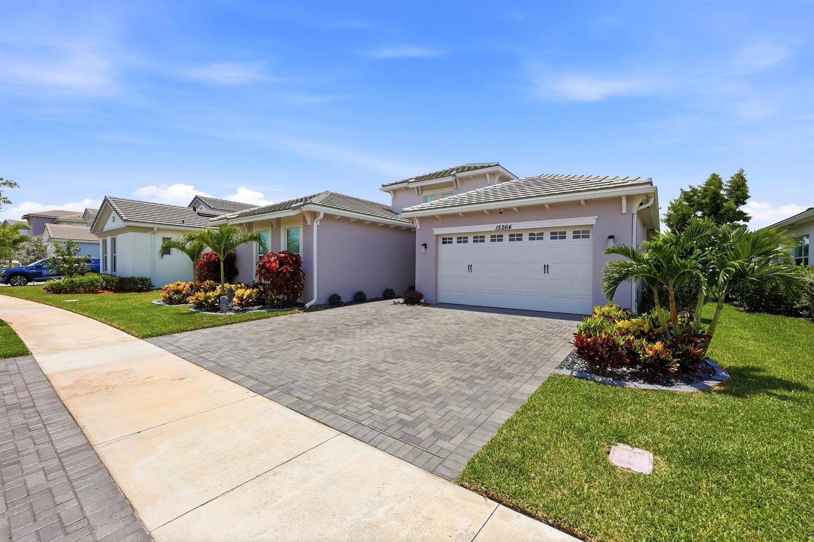 A light purple single-story house with a paved driveway, two-car garage, and tropical landscaping — 15264 Wildwood Circle, Westlake FL 33470, WESTLAKE, FL