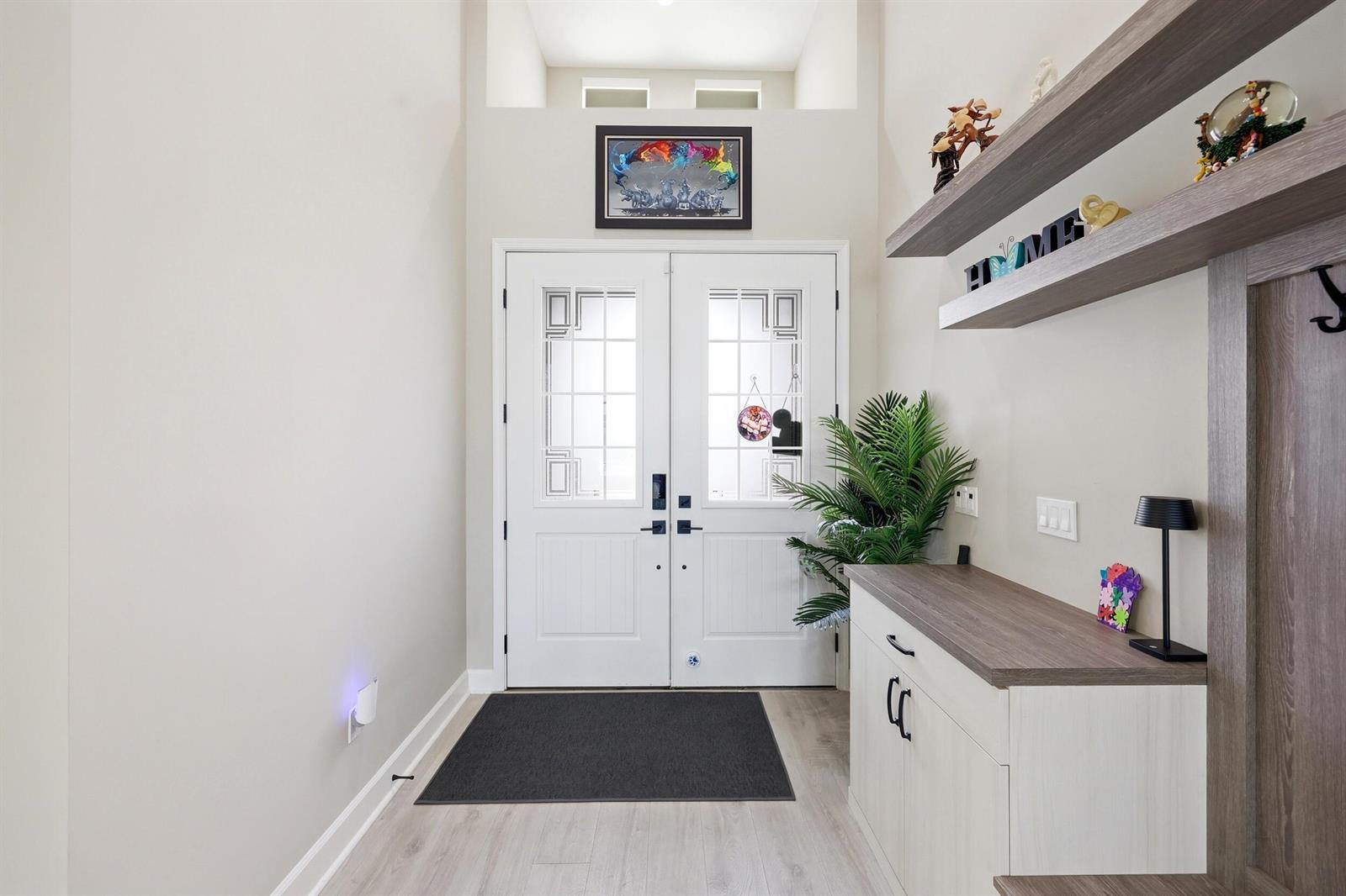 An entryway features double white doors, light wood flooring, floating shelves, and a storage cabinet — 15264 Wildwood Circle, Westlake FL 33470, WESTLAKE, FL