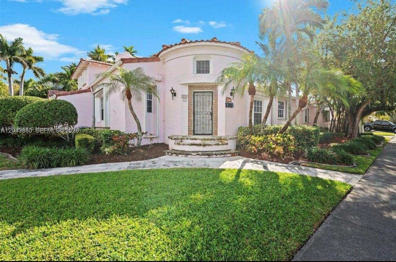 A pink, single-story house with a curved entryway and palm trees in the front yard — 1056 Harrison St, Hollywood FL 33019, HOLLYWOOD, FL