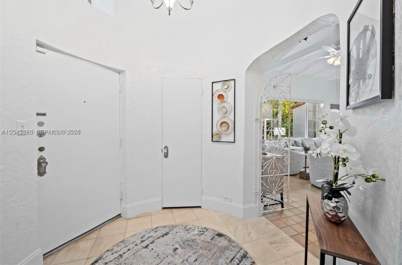 A white-walled entryway features a tiled floor, a round rug, and an arched doorway — 1056 Harrison St, Hollywood FL 33019, HOLLYWOOD, FL