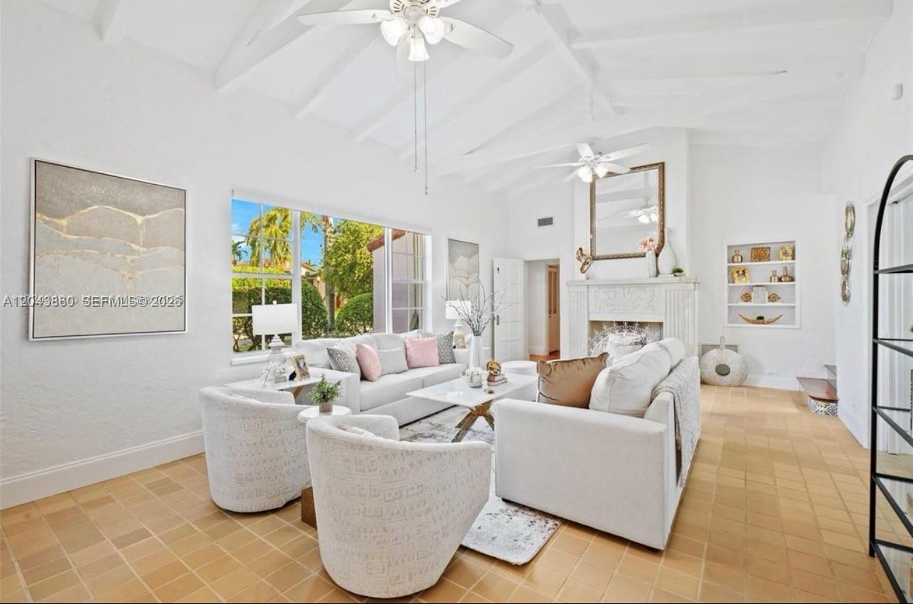 A bright living room features a vaulted ceiling, white furniture, a fireplace, and tile flooring — 1056 Harrison St, Hollywood FL 33019, HOLLYWOOD, FL