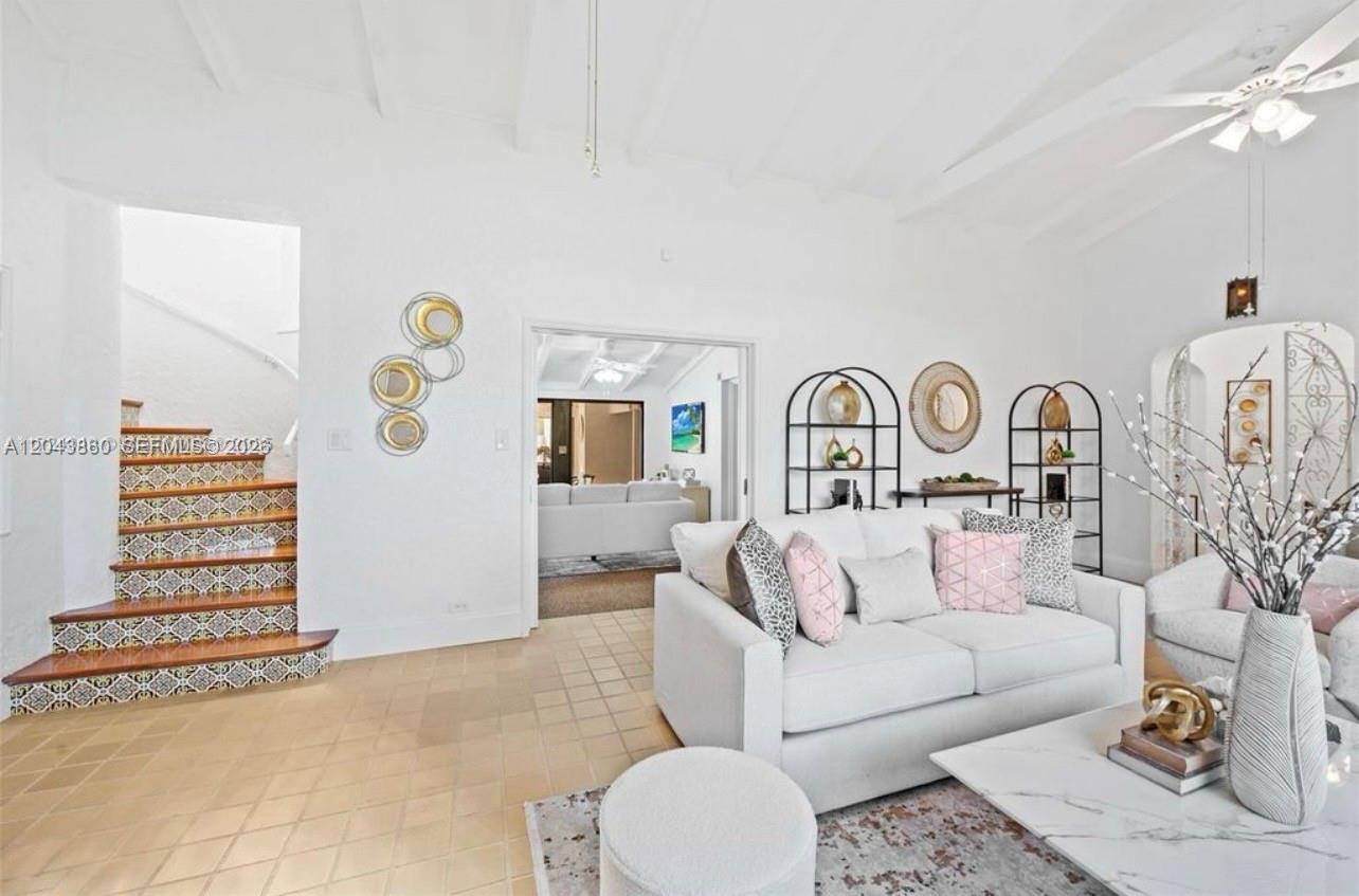 A living room features a white sofa, tiled floors, and a staircase with patterned risers — 1056 Harrison St, Hollywood FL 33019, HOLLYWOOD, FL