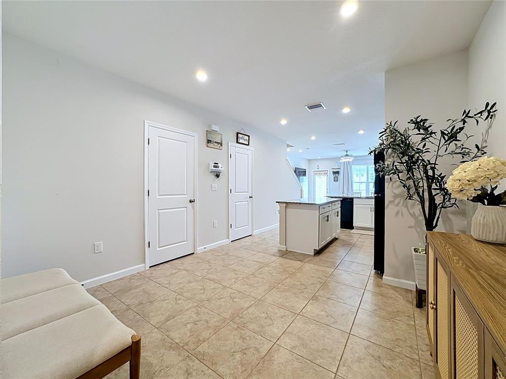 A tiled entryway leads into an open-concept kitchen with a central island and white cabinetry — 14172 CRIMSON AVENUE, BRADENTON, FL