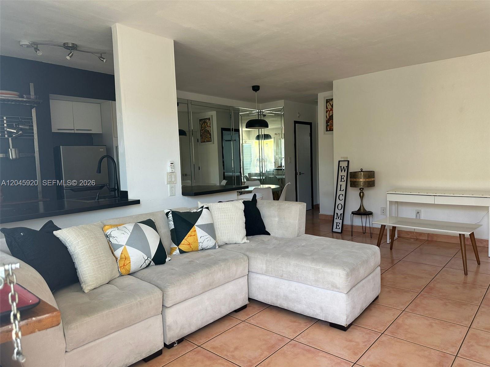 A living room with a sectional sofa, tiled floors, and an adjacent open kitchen area — 8101 Abbott Ave # 17, Miami Beach FL 33141, MIAMI BEACH, FL