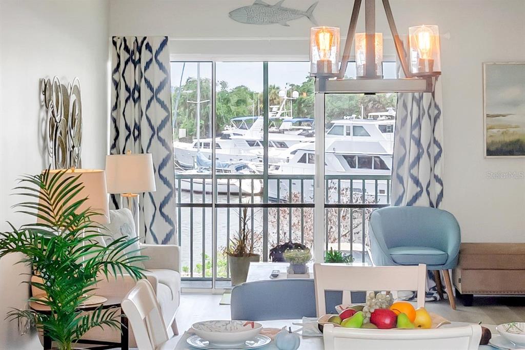 A dining and living area features a view of boats docked outside a sliding door — 715 S BEACH STREET UNIT 211D, DAYTONA BEACH, FL