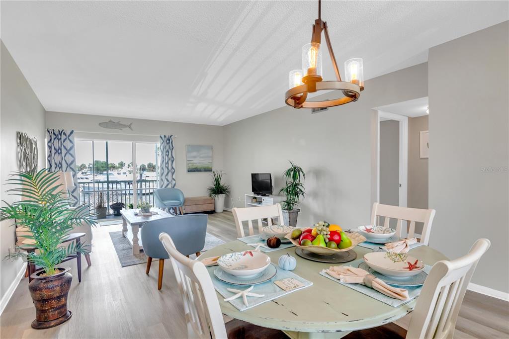 A dining area with a round table opens into a living room with balcony access — 715 S BEACH STREET UNIT 211D, DAYTONA BEACH, FL
