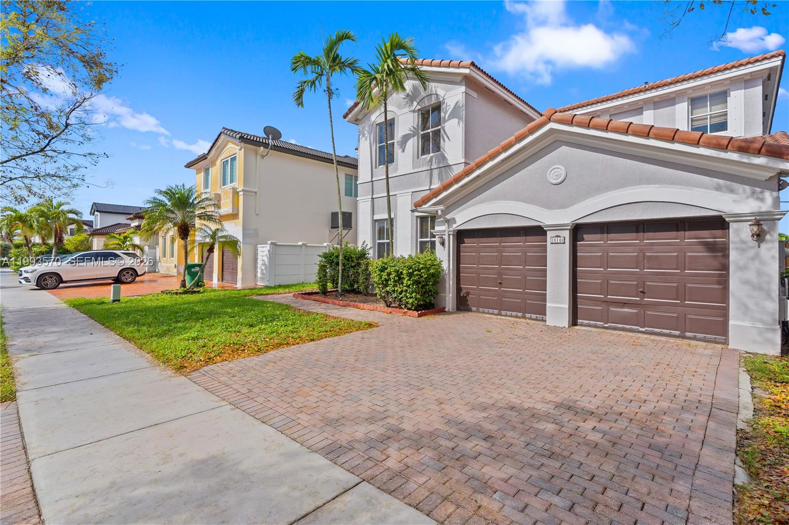 A two-story suburban house features a brick driveway, two garage doors, and palm trees — 18140 NW 90th Ave, Hialeah FL 33018, HIALEAH, FL