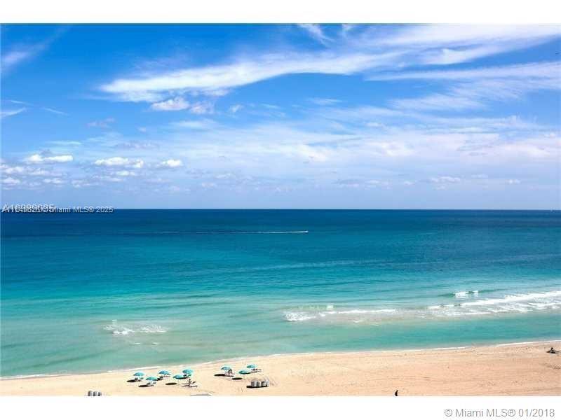A high-angle view of a sandy beach and the blue ocean under a cloudy sky — 5701 Collins Ave # 1008, Miami Beach FL 33140, MIAMI BEACH, FL