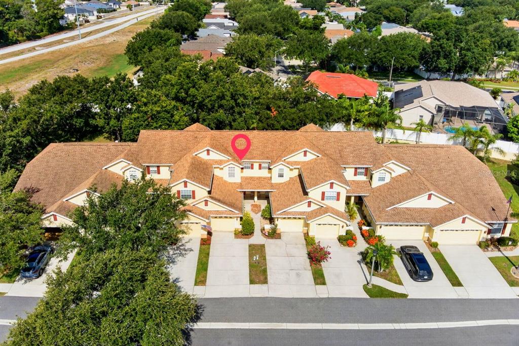 An aerial view shows the front exterior of a multi-unit townhouse complex with garages — 648 SPRING LAKE CIRCLE, TARPON SPRINGS, FL