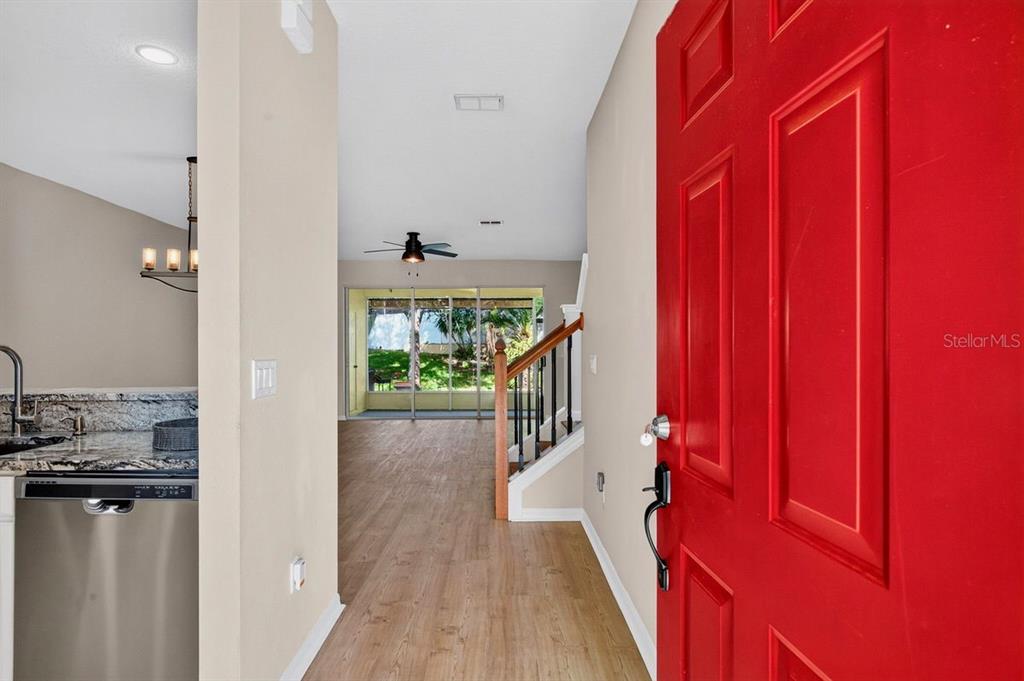 A view from a red front door into a home with wood-look flooring and stairs — 648 SPRING LAKE CIRCLE, TARPON SPRINGS, FL