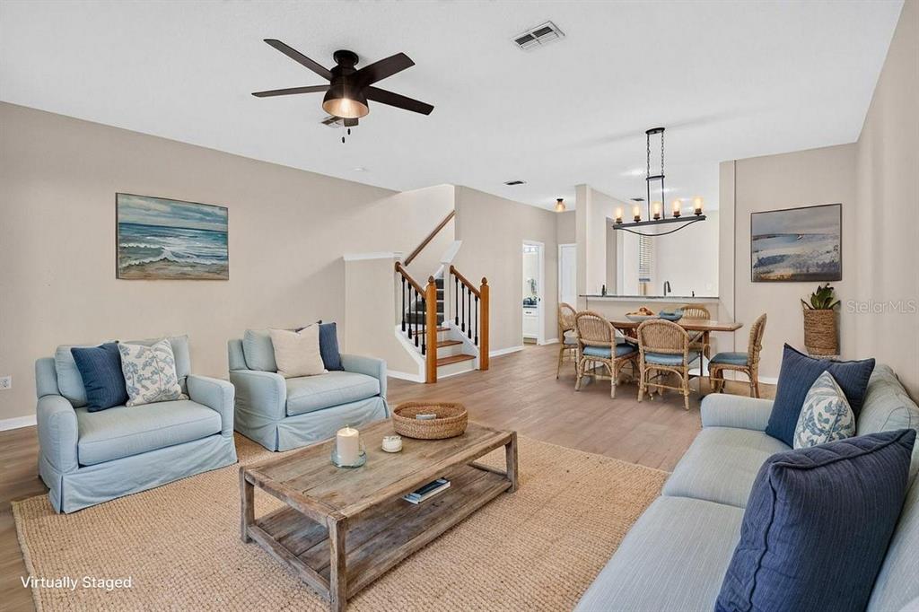 A living room and dining area feature light wood flooring, neutral walls, and wooden stairs — 648 SPRING LAKE CIRCLE, TARPON SPRINGS, FL