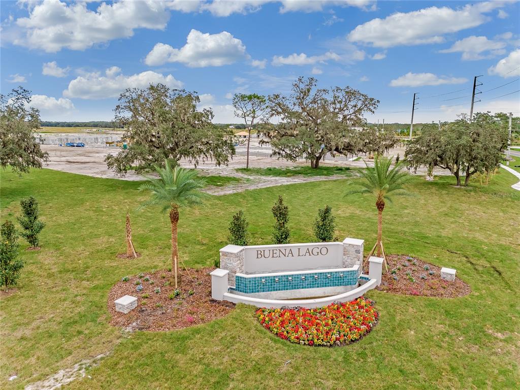 An aerial view shows the Buena Lago community entrance sign with a fountain and landscaping — 3499 MALAWI TRAIL, ST CLOUD, FL