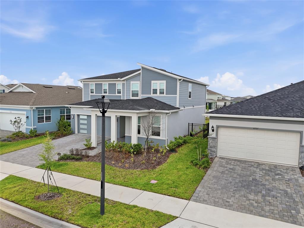 A two-story blue house with a gray roof and a paved driveway stands outdoors — 6711 WILLOW VIEW AVENUE, ORLANDO, FL