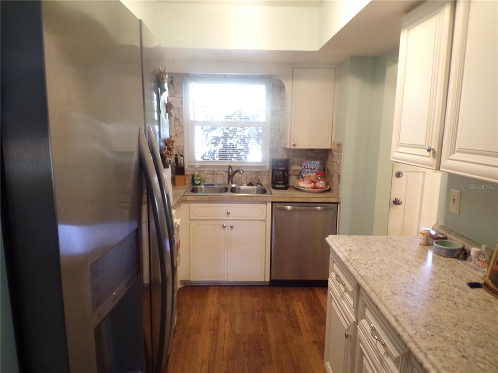 A kitchen features white cabinets, stainless steel appliances, granite countertops, and wood-look flooring — 670 PARK CIRCLE, BRADENTON, FL