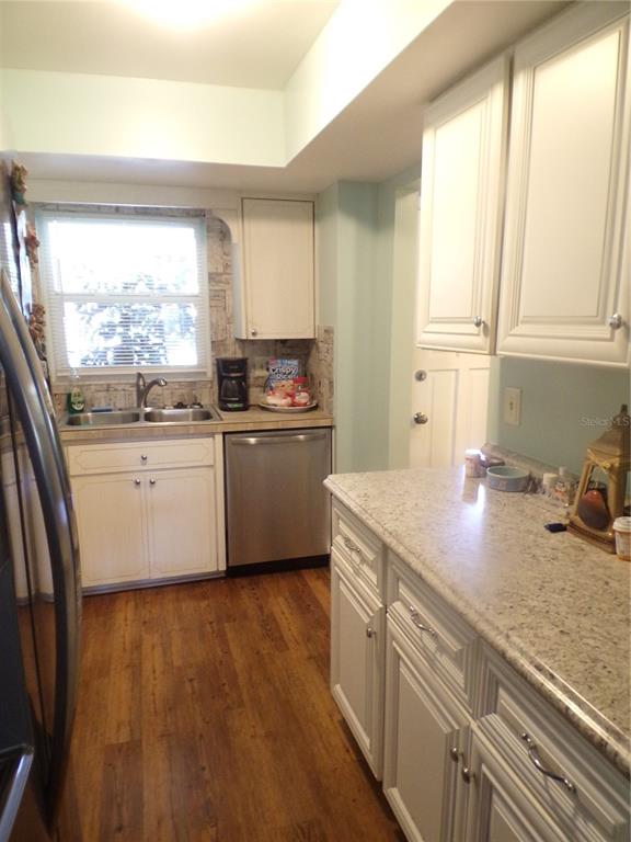 A kitchen with white cabinets, granite countertops, stainless steel appliances, and wood-look flooring — 670 PARK CIRCLE, BRADENTON, FL
