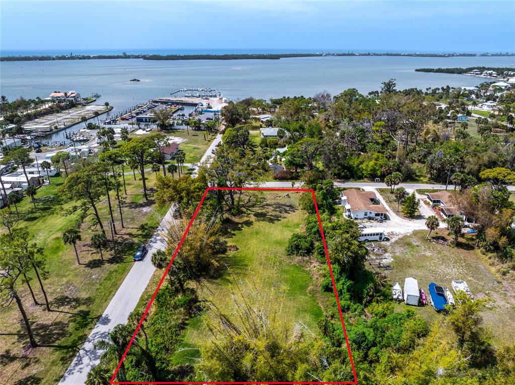 An aerial view shows a vacant, rectangular lot outlined in red near a coastal marina — PINEAPPLE STREET, ENGLEWOOD, FL