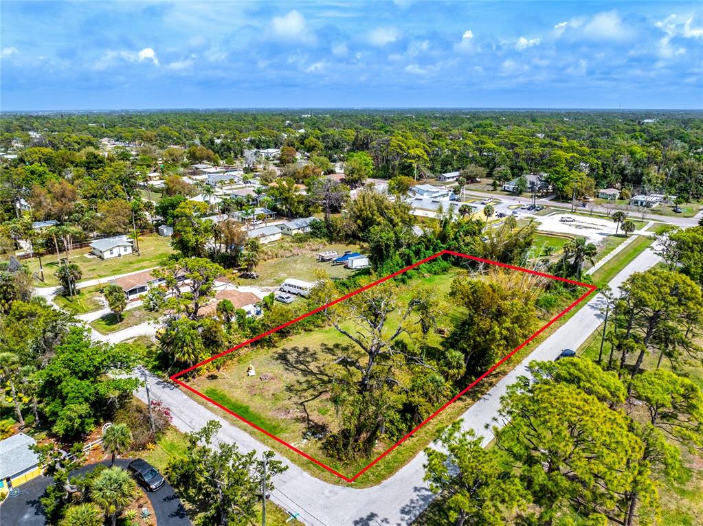 An aerial view shows a vacant, rectangular lot outlined in red surrounded by trees — PINEAPPLE STREET, ENGLEWOOD, FL