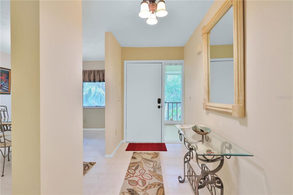 An entryway features a glass console table, a mirror, and a tile floor with a runner — 3450 WOOD OWL CIRCLE UNIT 284, BRADENTON, FL