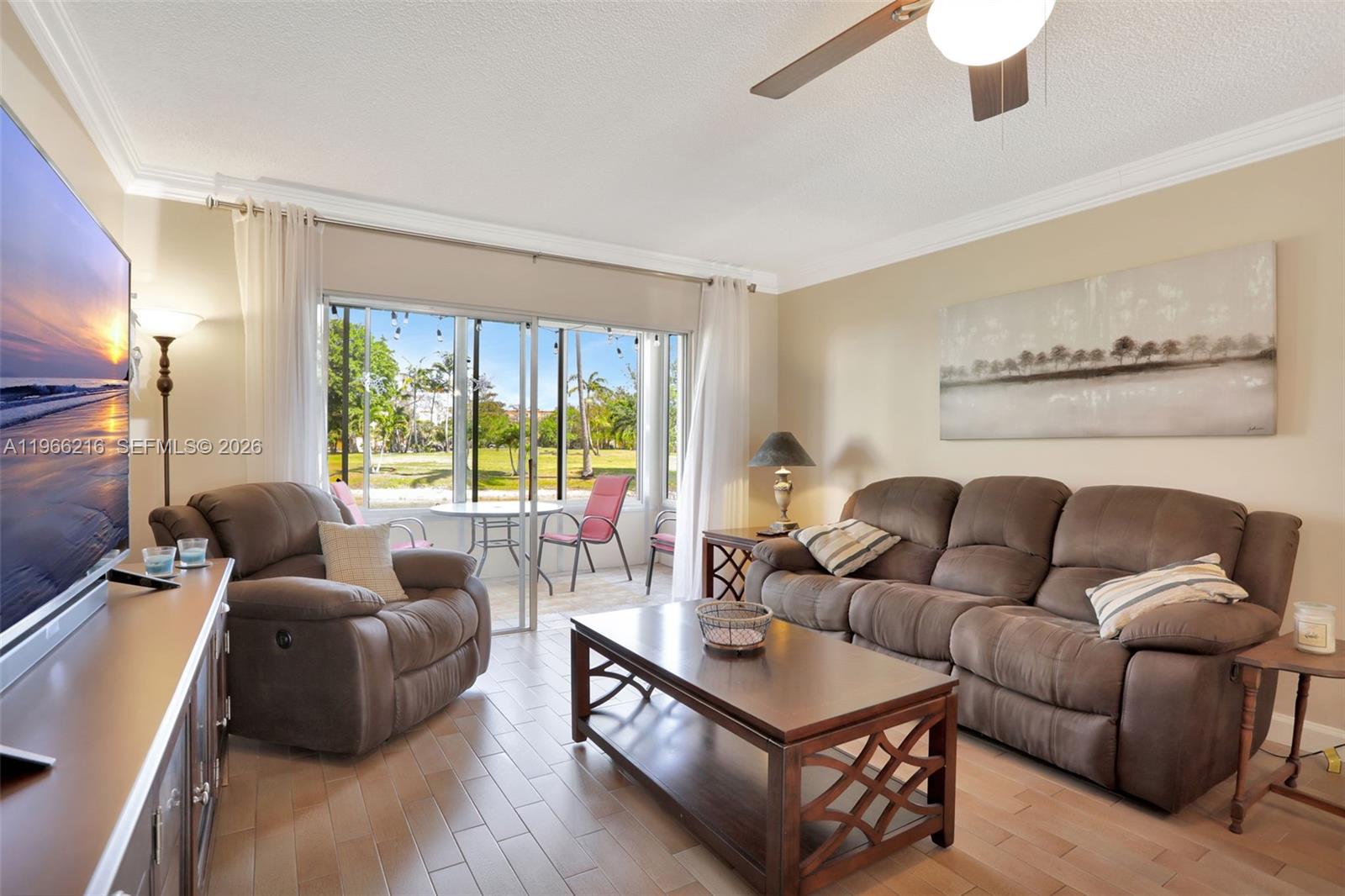 A living room features brown furniture, a coffee table, and a sliding door to a patio — 4311 NW 16th St # B103, Lauderhill FL 33313, LAUDERHILL, FL