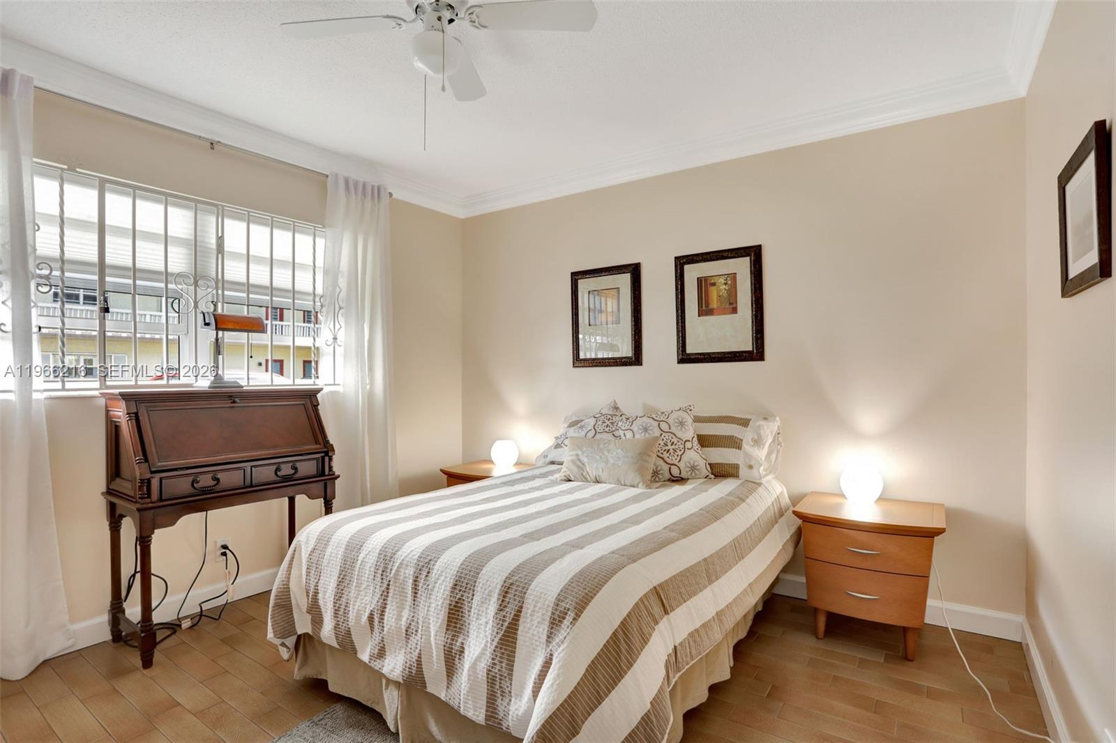 A bedroom features a bed with striped bedding, two nightstands, and a wooden desk — 4311 NW 16th St # B103, Lauderhill FL 33313, LAUDERHILL, FL