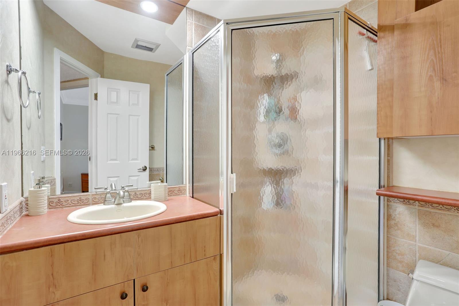 A bathroom features a wood vanity with a sink, a corner shower, and tiled walls — 4311 NW 16th St # B103, Lauderhill FL 33313, LAUDERHILL, FL