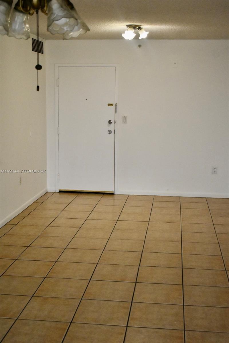 This room features white walls, beige tile flooring, and a white entry door — 616 NW 26th Ave # 210, Miami FL 33125, MIAMI, FL